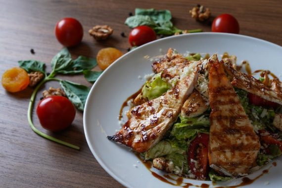 Delicious grilled chicken salad served with fresh tomatoes and walnuts on the side.